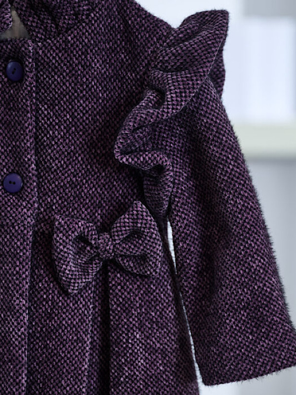 Παλτό, εμπνευσμένο από την βικτωριανή εποχή, από βελουτέ ύφασμα με περίτεχνη πλεκτή υφή. Οι μοναδικές λεπτομέρειες όπως ο μάο γιακάς, το λοξό βολάν στα μανίκια, τα φιογκάκια αλλά και οι κουφόπιετες το καθιστούν ιδανικό για την απόλυτη χειμερινή βάπτιση. Μια επιλογή ταιριαστή με όλα τα φορέματα της συλλογής.