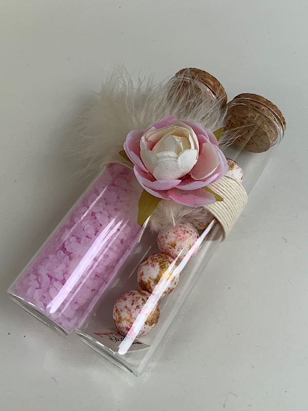 Διπλός γυάλινος σωλήνας με 5 κουφέτα choco crispy Χατζηγιαννάκη και άλατα μπάνιου διακοσμημένη με υφασμάτινο λουλούδι και φτερό .  Διαθέσιμη σε πολλές αποχρώσεις. Για οποιαδήποτε αλλαγή επικοινωνήστε μαζί μας 