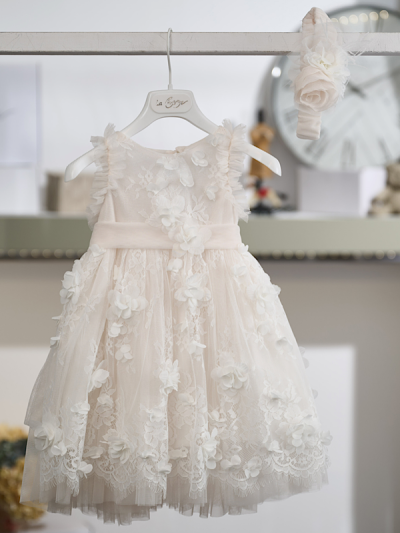 Η ρομαντική πολυτέλεια και η πλούσια διακόσμηση συνθέτουν ένα εντυπωσιακό βαπτιστικό φόρεμα σε απαλή βανίλια απόχρωση, εμπνευσμένο από τη διαχρονική αισθητική του μπαρόκ. Τα φίνα υφάσματα και οι περίτεχνες λεπτομέρειες δημιουργούν μια ιδιαίτερα κομψή και ξεχωριστή εμφάνιση.